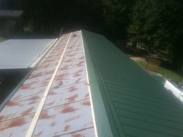 Old rusted panels beside newly installed green metal roofing — Wind Damage Roof Repair by Roofing Brothers in Jerome
