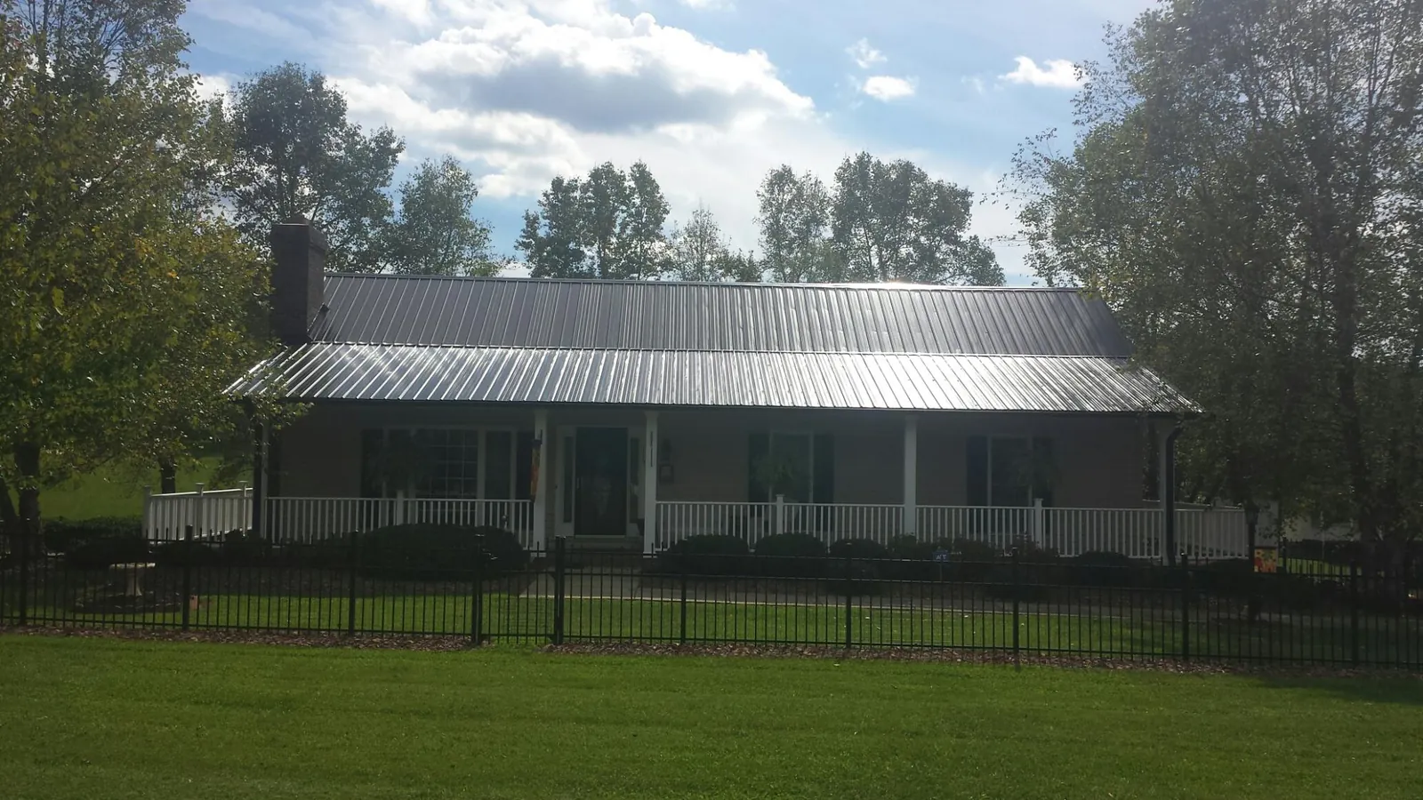 Gray metal roof on a brick ranch with a full width front porch — Gutter Guard Installation work by our crew in Jerome